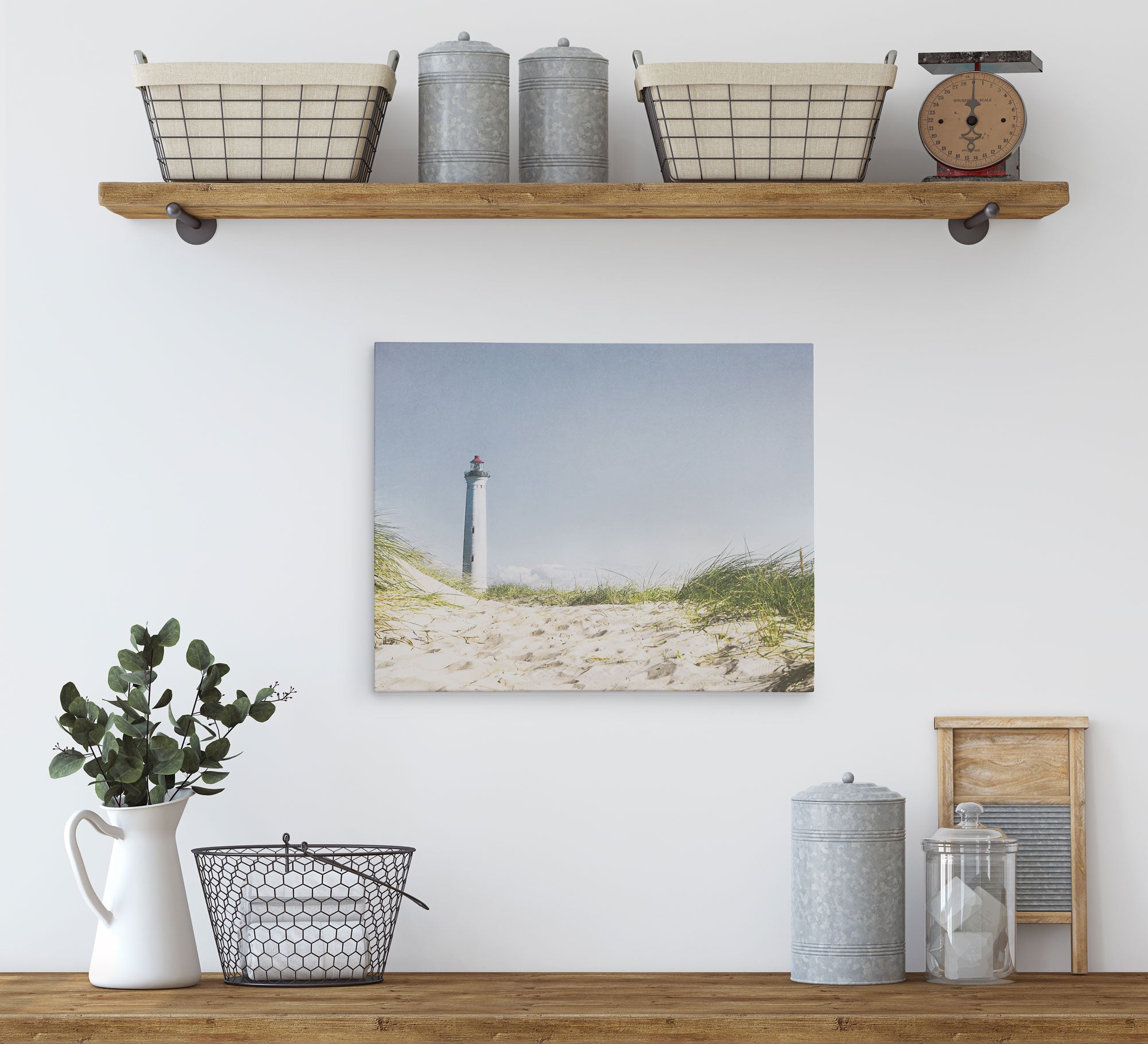 Nestled in a minimalist kitchen shelf setup adorned with rustic decor and coastal prints from Offley Green, the top shelf features two baskets, two metal jars, and a vintage scale. Below hangs an 11x14 Coastal Canvas Print of a lighthouse from Offley Green&#39;s collection. On the countertop, you&#39;ll find a metal basket, a ceramic pitcher with plants, and additional metal jars.