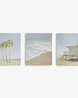 The Offley Green Set of 3 Canvas includes a left image of palm trees on sand, a center photo of ocean waves hitting the shore, and a right scene featuring a lifeguard tower. Each artist-grade canvas captures the tranquil coastal vibe perfectly.