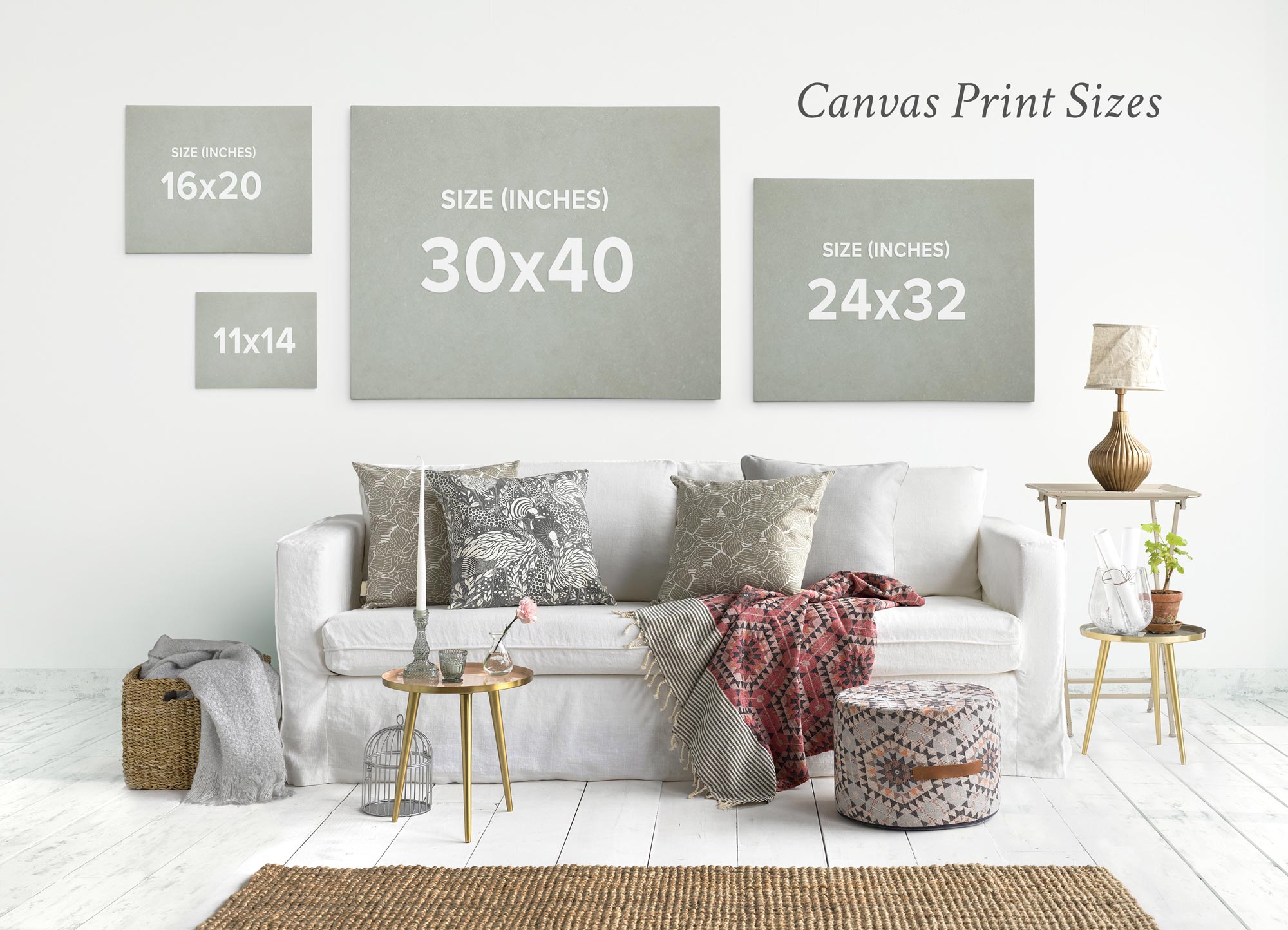 A cozy living room features a white sofa adorned with patterned pillows and a throw blanket. Three canvas prints of different sizes, including some vibrant Offley Green 24x30 California Canvas Prints (Choose from 10+ Designs), grace the wall beneath the text &quot;Canvas Print Sizes.&quot; A rug and small tables complete the decor.