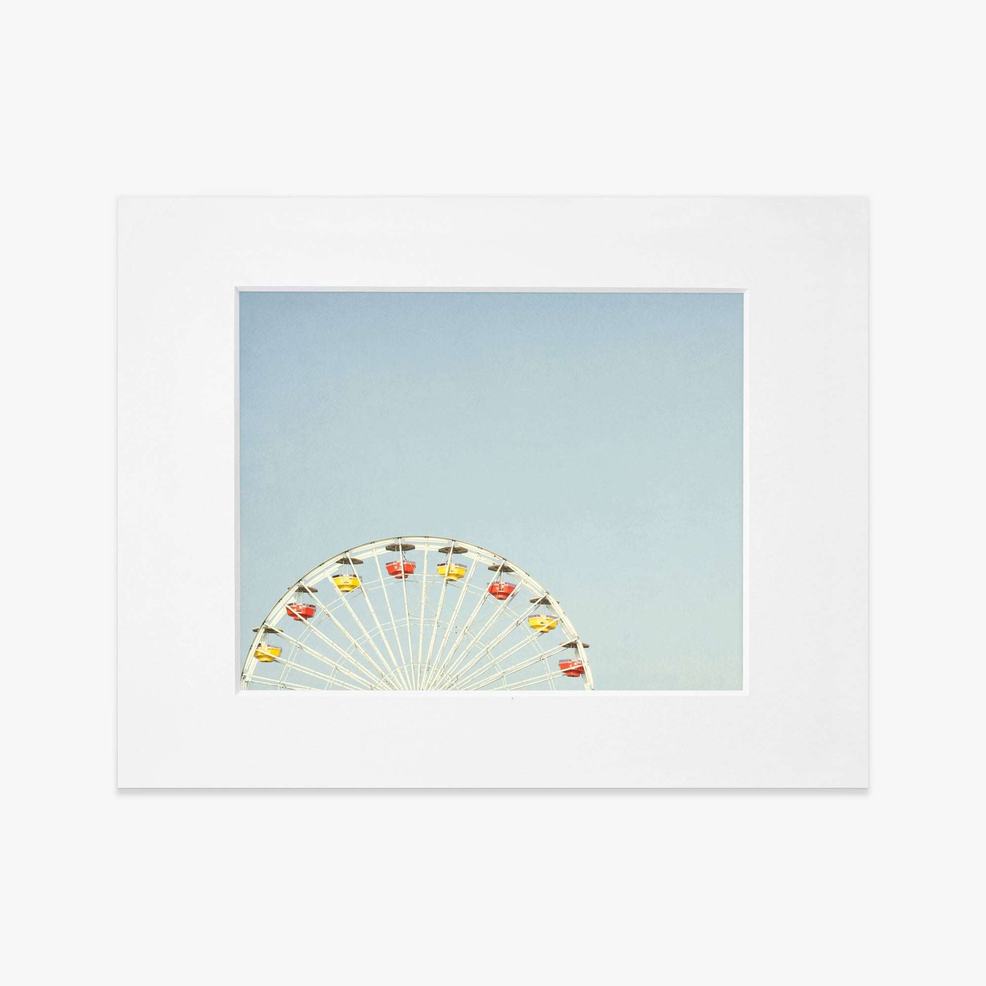 A &#39;Ferris Blue&#39; ferris wheel with colorful cabins set against a clear blue sky, framed within a white border on archival photographic paper by Offley Green.