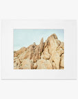 A framed photograph of a rugged desert landscape featuring large, weathered rock formations under a clear sky. The image is centered within a white matting inside an Offley Green frame and printed on archival photographic paper.
