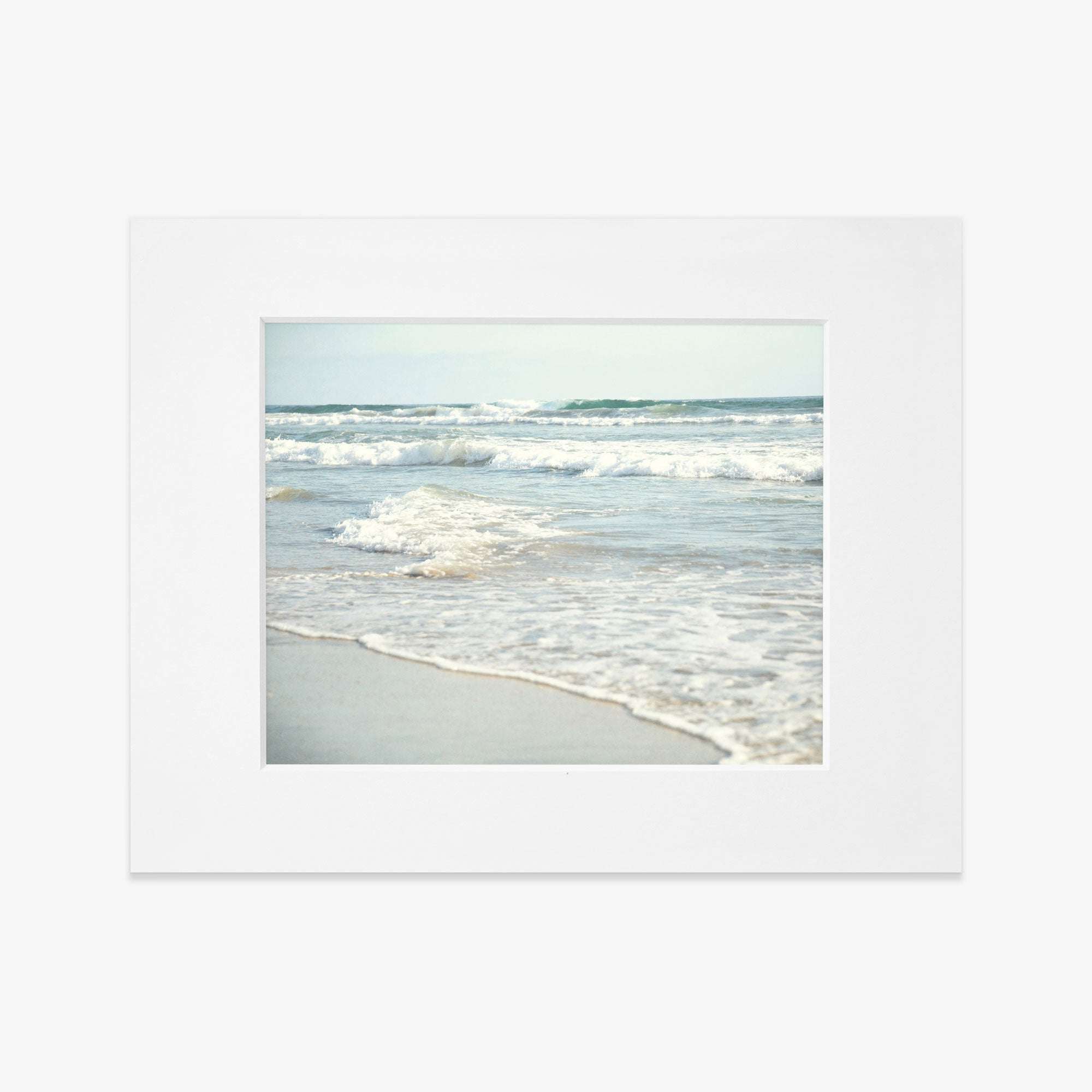 A photograph of Carlsbad State Beach, capturing the gentle waves lapping onto sandy shores, depicted in a simple white frame. This is the Offley Green Coastal Beach Print in California &#39;Surf and Sun&#39;.