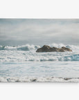 Experience a serene ocean scene where gentle waves lap against a rocky outcrop beneath a cloudy sky. The distant horizon merges seamlessly with the overcast atmosphere, eliciting feelings of tranquility and calm, ideal for coastal decor. This ready-to-hang 11x14 Coastal Canvas Print by Offley Green (available in over 10 designs) brings the peaceful seaside ambiance into any room.