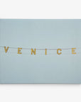 A minimalist image features the word "VENICE" spelled out in large illuminated letters, hanging on wires against a pale blue sky – perfect for the 30x40 California Canvas Print by Offley Green. Choose from 10+ designs to enhance your wall art collection.