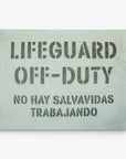 An 11x14 California Canvas Print (Choose from 10+ Designs) by Offley Green featuring a sign with bold stenciled text reading "LIFEGUARD OFF-DUTY" in English and "NO HAY SALVAVIDAS TRABAJANDO" in Spanish against a light background, perfect as wall art for those who love California prints.