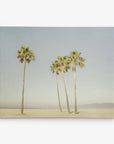 A serene beach scene featuring six palm trees standing tall against a clear sky. The sand stretches to the horizon with a hazy outline of distant mountains or a coastal landscape in the background. This tranquil California-themed artwork, from Offley Green's 8x10 California Canvas Print collection, is available as a gallery wrap and would make perfect wall art. Choose from over 10 stunning designs to find your ideal piece!