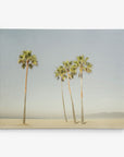 A serene beach scene featuring five tall palm trees standing on a sandy shore, spaced out against a clear sky. In the hazy background, subtle outlines of distant mountains and a minimalistic seascape can be seen—a perfect 24x30 California Canvas Print (Choose from 10+ Designs) from Offley Green.