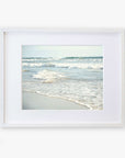 A framed photograph of Carlsbad State Beach with gentle waves and soft sand, displayed against a white background. The frame is simple and white, enhancing the tranquil Coastal Beach Print in California 'Surf and Sun' by Offley Green.