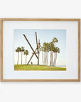 An unframed artwork depicting the Offley Green 'V is for Venice' sculpture, a surreal scene with oversized wooden clothespins partially buried in a grassy field, surrounded by tall palm trees under a clear blue sky.