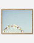 A framed picture showing the top half of a Ferris wheel with colorful cabins against a clear blue sky background, captured on archival photographic paper. This is the Blue Minimalist Wall Decor, 'Ferris Blue' by Offley Green.