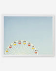 A framed picture of the Blue Minimalist Wall Decor 'Ferris Blue' by Offley Green, with a white ferris wheel and yellow and red gondolas at Santa Monica Pier, half-visible against a clear blue sky.