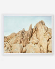 An unframed image of a rugged rock formation with sharp and rounded boulders extending towards a clear sky, depicted in a natural, earthy palette by Offley Green's Joshua Tree Print, 'Joshua Rocks.'