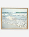 A framed photograph of Carlsbad State Beach displaying gentle waves breaking along the shoreline, with a blurred view of the ocean's horizon in the background, featuring the Coastal Beach Print in California 'Surf and Sun' by Offley Green.