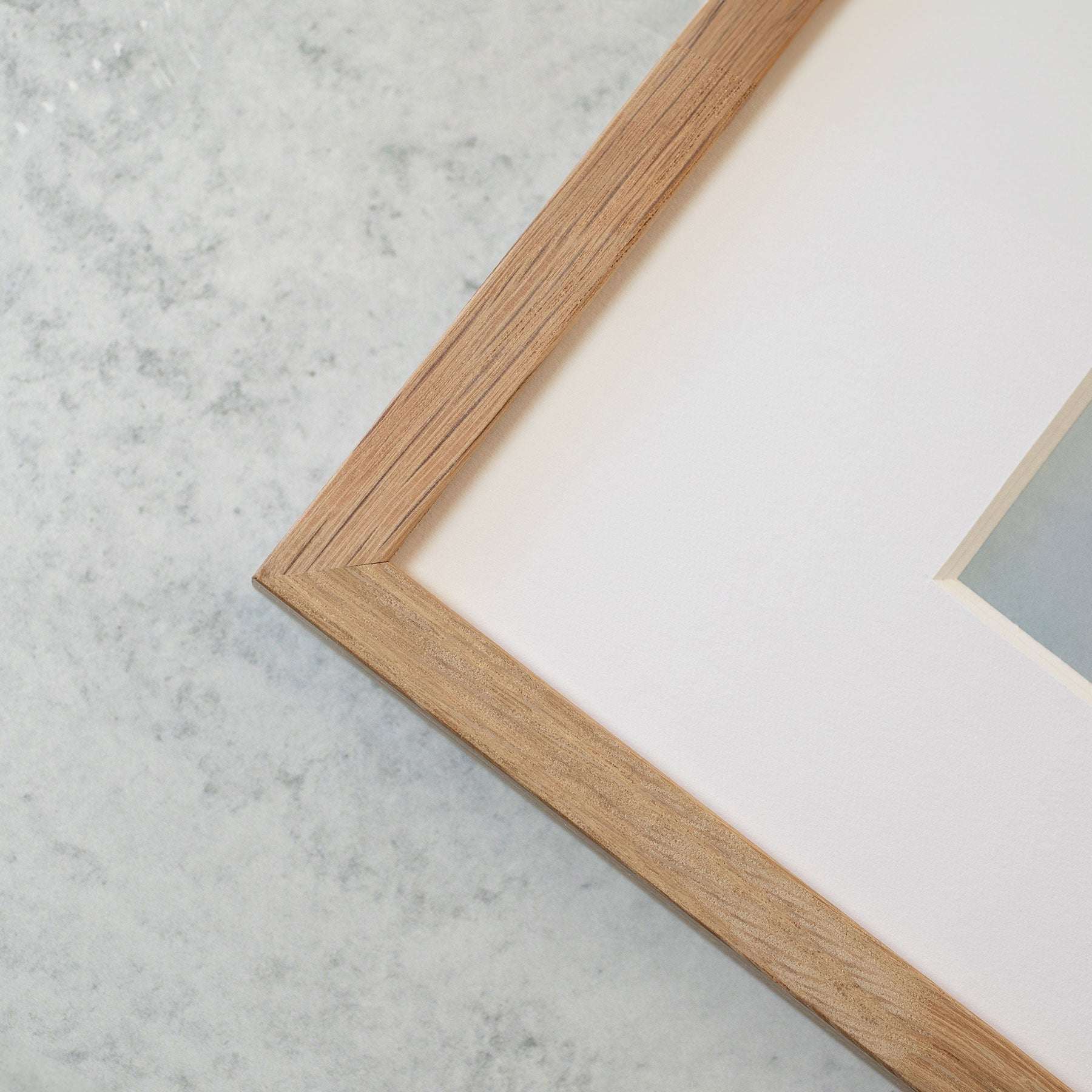 Close-up of an &#39;Abstract Green Botanical Print, Desert Fireworks&#39; frame corner on a marble surface, showcasing the frame&#39;s fine wood grain and the smooth, off-white matte border inside it with archival photographic paper.