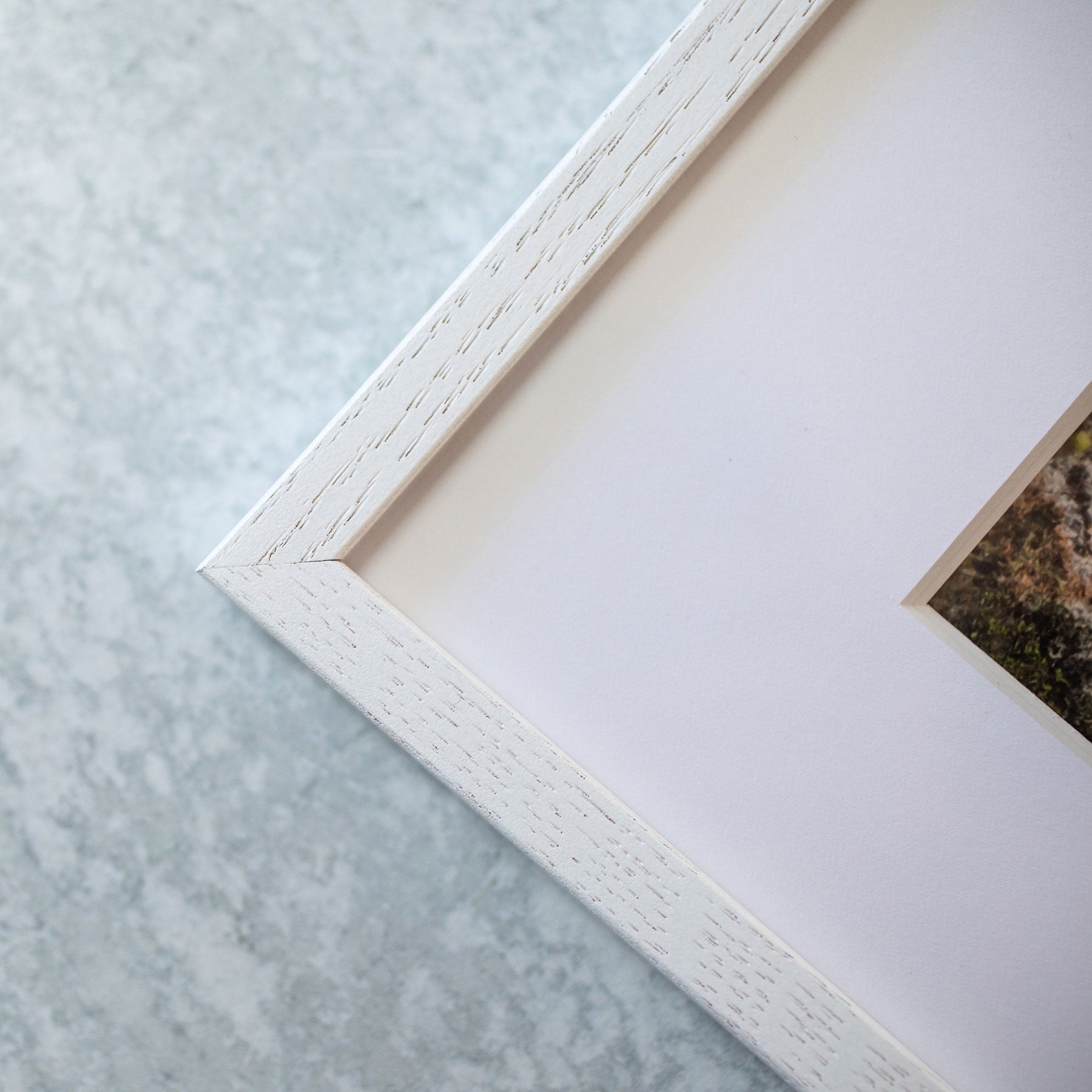 Close-up of a corner of a white textured Offley Green picture frame on a light gray background, partially showing a photograph printed on archival photographic paper inside the Venice Beach Landmark Sculpture, &#39;V is for Venice&#39;.