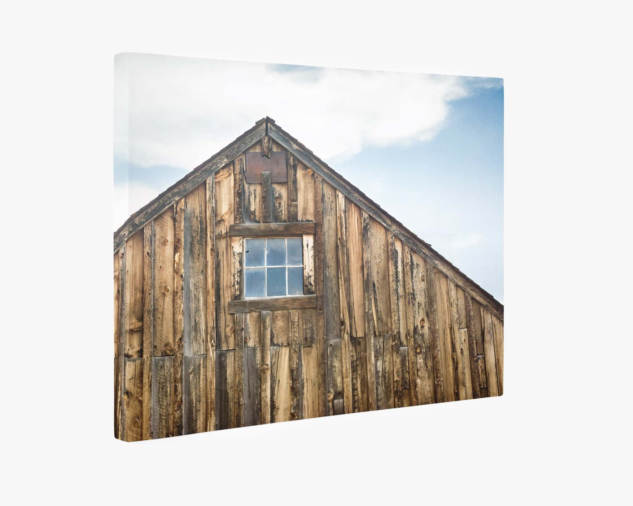 An Offley Green Farmhouse Wall Art, Rustic Barn Decor, 'Old Barn at Bodie' featuring a rustic farmhouse wooden barn wall with a centered small window near the roof peak, set against a backdrop of a partly cloudy sky, crafted on premium artist-grade canvas.
