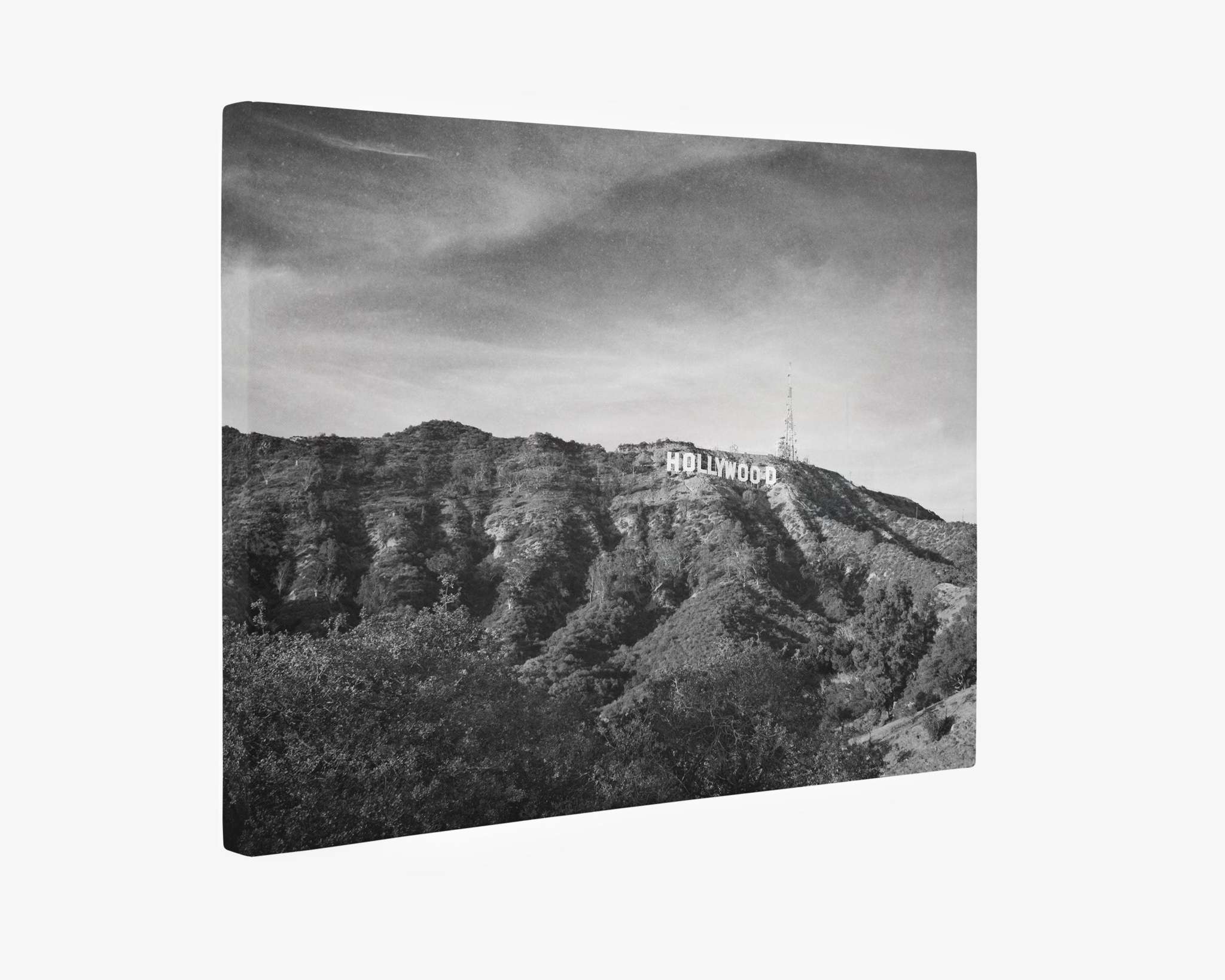 A black-and-white photograph featuring the iconic Hollywood sign perched on a hill in Los Angeles, California. The sign is surrounded by rugged hills and scraggly vegetation, set against a partly cloudy sky, reminiscent of film noir imagery. Perfect for canvas gallery wrap prints like the Hollywood Sign Black and White Vintage Wall Art, &#39;Old Hollywood&#39; by Offley Green.