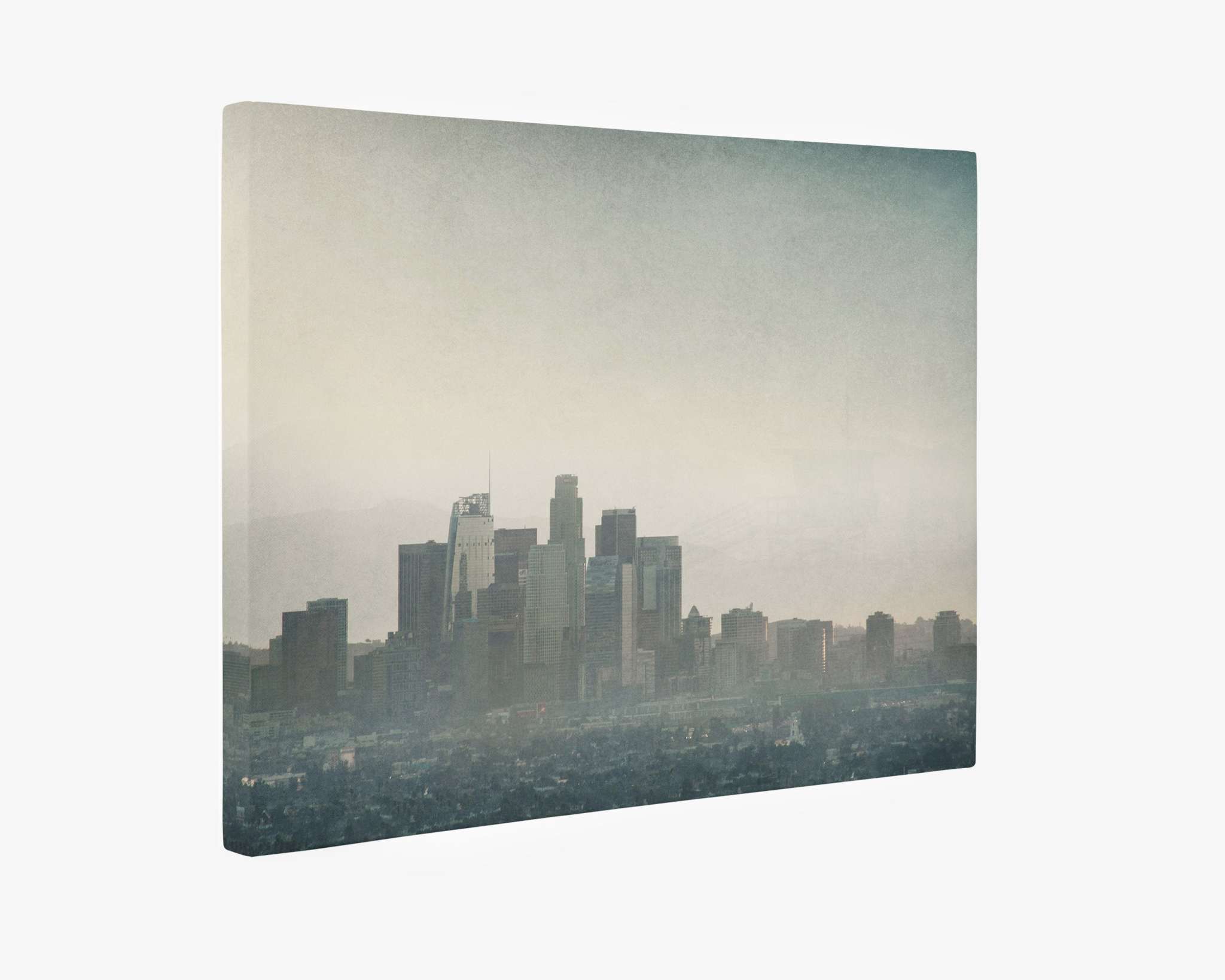 A Downtown Los Angeles Canvas Wall Art, 'Stormy La La Land' by Offley Green depicting a moody downtown Los Angeles scene with tall buildings and skyscrapers partially shrouded in mist against a grayish sky. The overall tone is muted and serene, evoking a sense of calm and stillness in the urban environment. Printed on premium artist-grade canvas for lasting elegance.