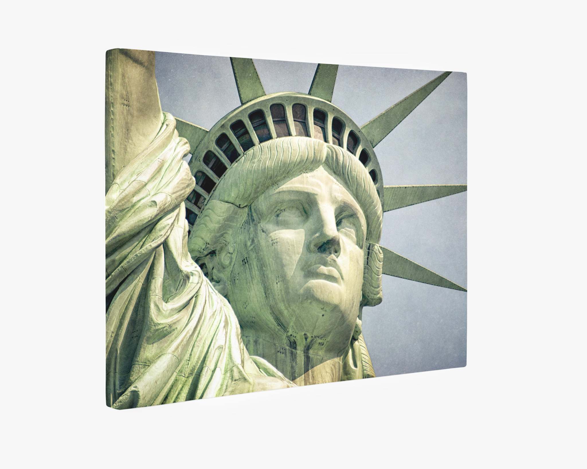 Close-up shot of the upper part of the Statue of Liberty against a cloudy sky. The image captures details of the statue's face, crown, and the rays extending from it. The statue is greenish due to oxidation of its copper surface. Available as a canvas gallery wrap on premium artist-grade canvas.

Introducing New York City Canvas Wall Art, 'Face of Liberty' by Offley Green.